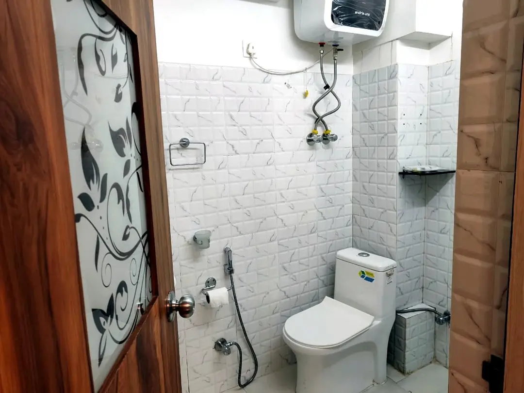 Tiled bathroom with water heater and frosted glass door