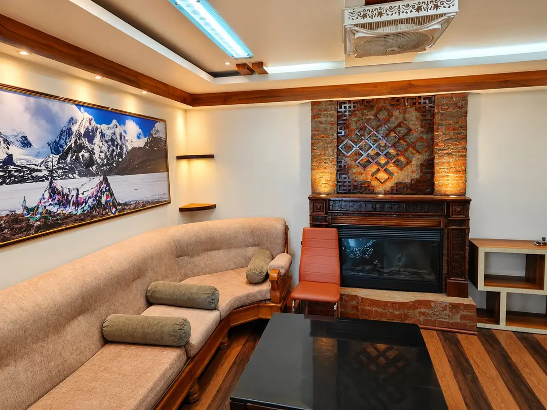 Suite sitting room with a curved sofa, carved fireplace surround with endless-knot fretwork and a large mountain photograph