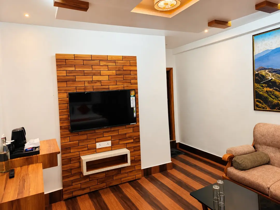 Suite sitting area with a wall-mounted television on a timber feature wall and a tea tray